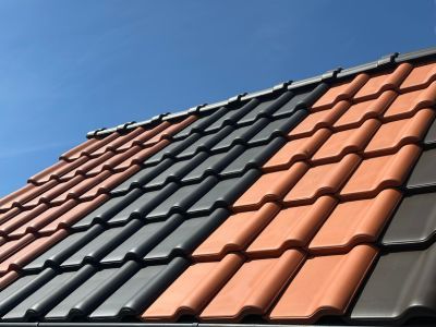 Dachziegel in Rot und Grau gestapelt &ndash; zeigt Materialien f&uuml;r wetterfeste und langlebige Dachkonstruktionen