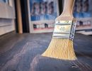 Ein Pinsel tr&auml;gt Lasur auf Holz auf &ndash; zeigt die Veredelung und den Schutz von Holzoberfl&auml;chen im Handwerksbereich
