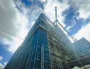 Ger&uuml;st und Kran an Hochhaus-Baustelle &ndash; zeigt gro&szlig;fl&auml;chige Rohbauarbeiten bei mehrgeschossigen Geb&auml;uden