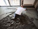 &bdquo;Eine Person gl&auml;ttet frischen Betonboden &ndash; zeigt Arbeitsschritte beim fachgerechten Einbau und Ausgleich von B&ouml;den