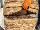 Person mit Handschuhen h&auml;lt dicke D&auml;mmmatte, zeigt thermische Isolierung mit Mineralwolle oder Glasfaser